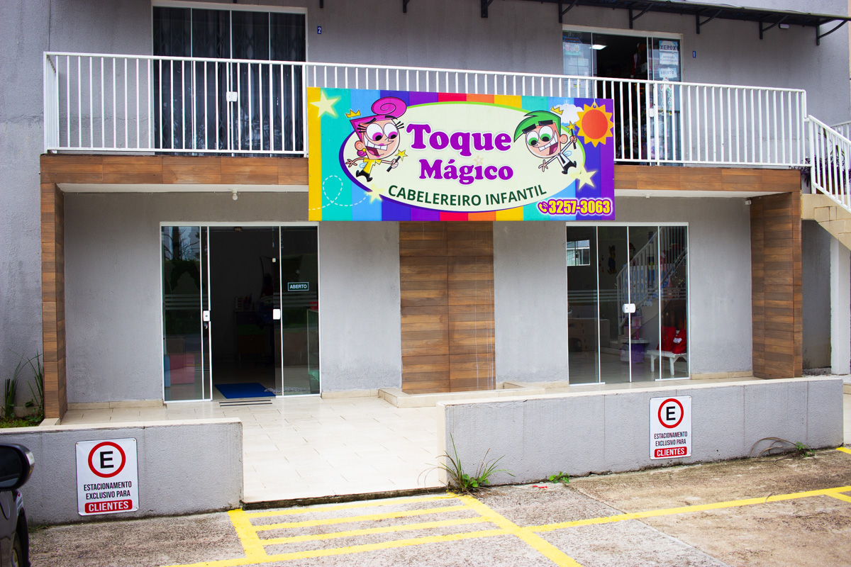 Fachada do Toque Mágico com letreiro colorido de desenho animado escrito Toque Mágico Cabeleireiro Infantil